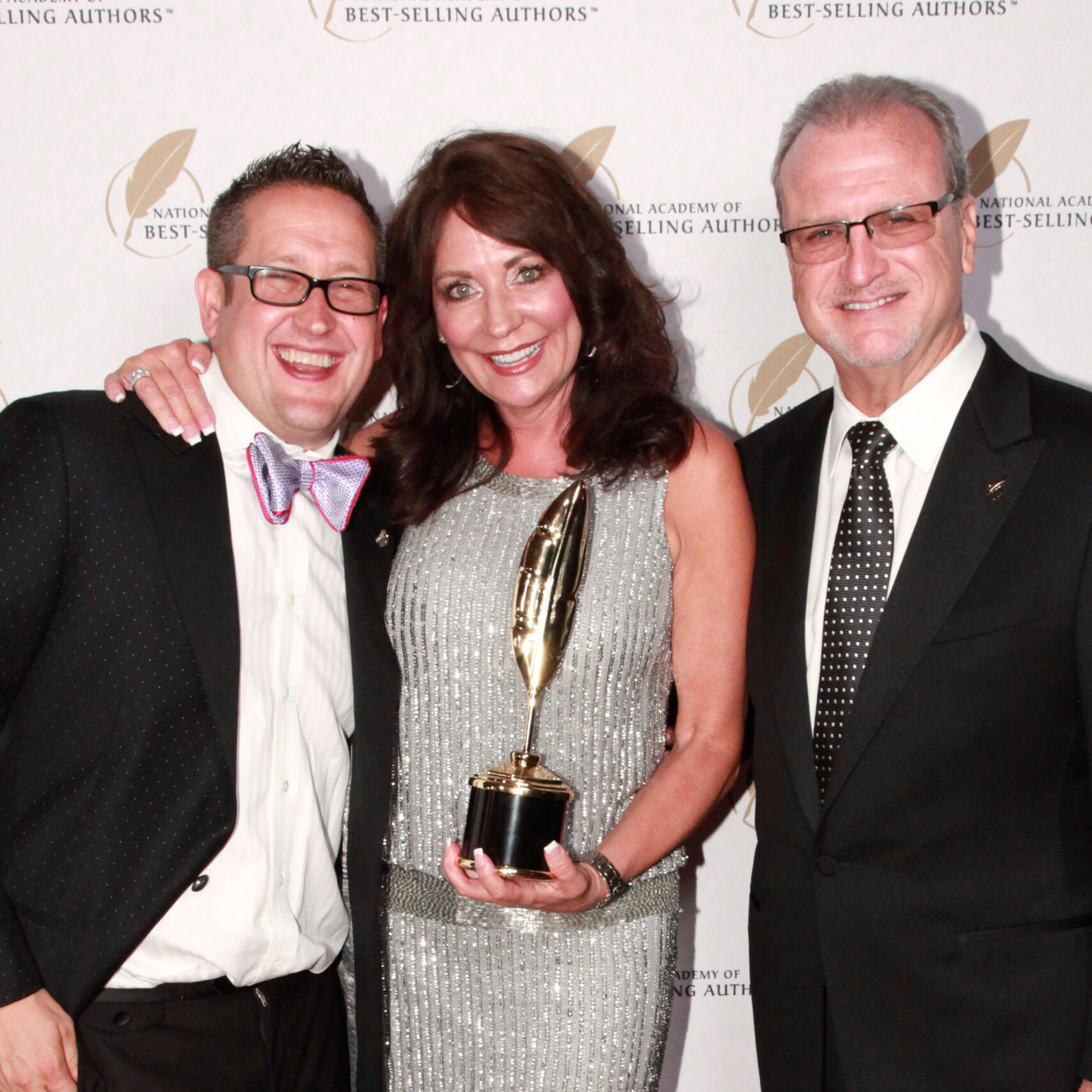 Cindy Ertman holding an award next to two men at a national Academy of best-selling authors event